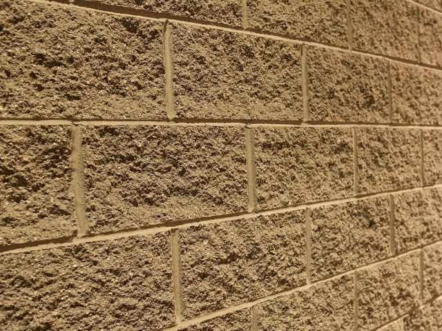 Muro exterior revestido con hormigón impreso vertical molde ladrillo en tono arena