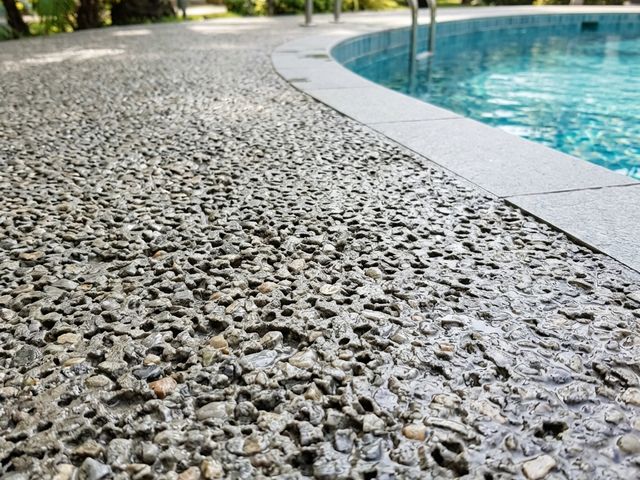 Playa de piscina con pavimento de hormigón poroso de árido visto